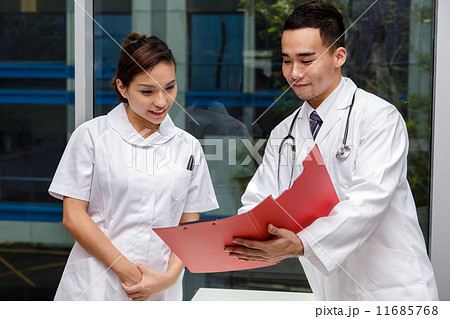 Young Asian doctor passing instruction to a nurse 11685768