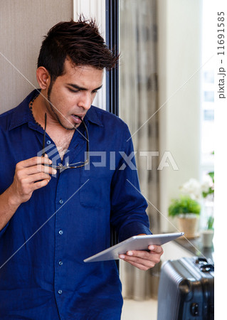 Asian man using digital tablet, contemplating. 11691585
