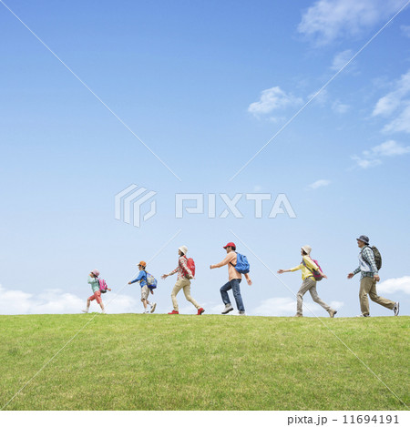 リュックを背負い草原を歩く三世代家族 11694191