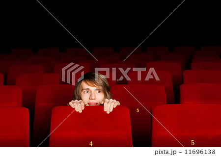 young man in the cinema hiding behind a chair 11696138