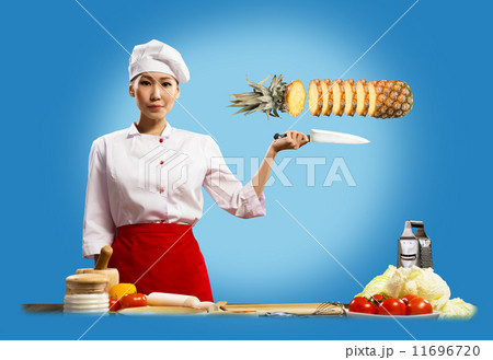 Asian female chef cuts pineapple 11696720