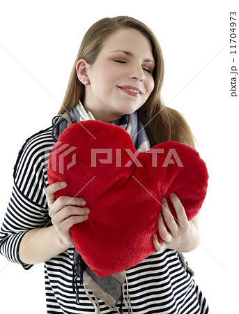Beautyful young and smiling woman embraces heart shaped pillow with her hands Beautyful young and smiling woman embraces heart shaped pillow with her hands 11704973