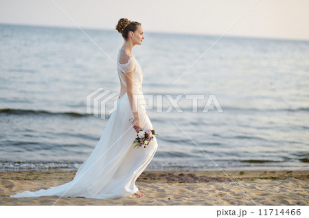 Bride walking along sea coast on sunset Bride walking along sea coast on sunset 11714466