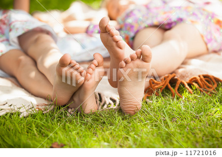 two sisters feet lying on grass at park 11721016