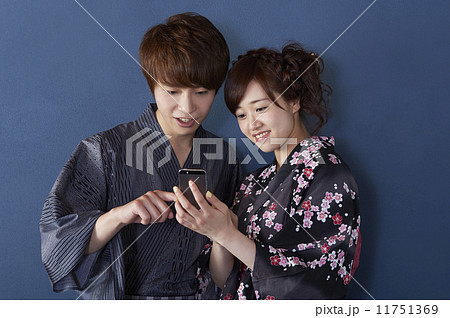 携帯電話で調べる浴衣の男女 携帯電話で調べる浴衣の男女 11751369