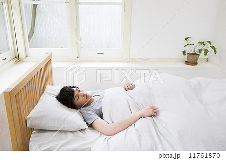 ベッドで寝る若い男性の写真素材