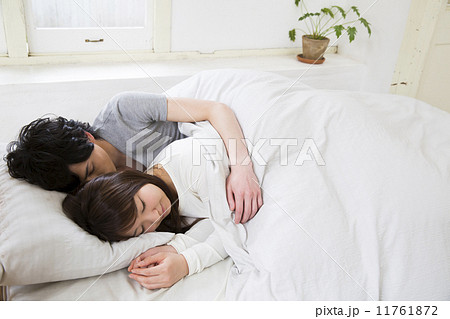 ベッドで眠る男女の写真素材