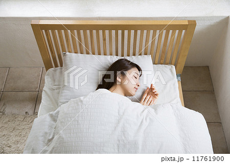 ベッドで寝る女性の写真素材