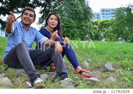 A young and handsome asian man pointing at a direction to his girlfriend while they were seated A young and handsome asian man pointing at a direction to his girlfriend while they were seated 11762026