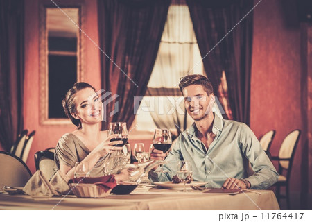 Beautiful young couple with glasses of wine in restaurant Beautiful young couple with glasses of wine in restaurant 11764417