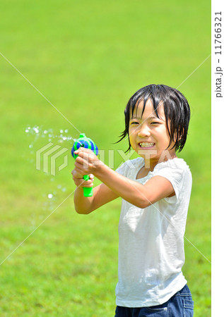 水鉄砲で遊ぶ女の子 芝生広場 の写真素材