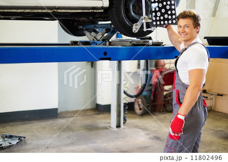 Young serviceman checking wheel alignment  in a car workshop 11802496