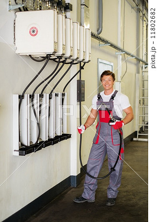 Cheerful serviceman holding hose with unbottled motor oil in a car workshop 11802682