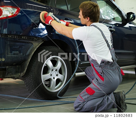Serviceman polishing car body with machine  in a workshop 11802683