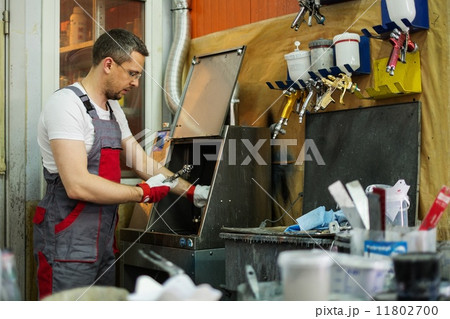Serviceman cleaning airbrush gun in a car body workshop Serviceman cleaning airbrush gun in a car body workshop 11802700
