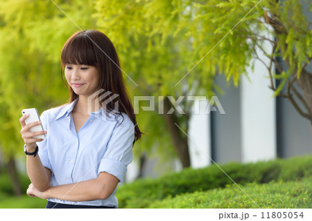 Successful young office lady using smart phone along promenade during break time 11805054