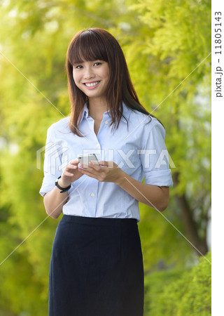 Successful young office lady using smart phone along promenade during break time Successful young office lady using smart phone along promenade during break time 11805143