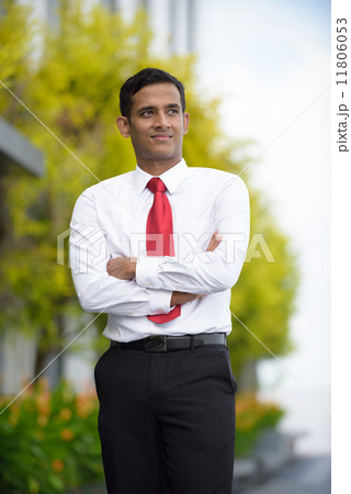 Portrait of successful young Indian corporate executive standing along promenade 11806053
