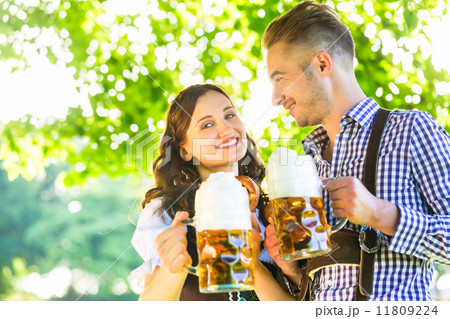 German couple in Tracht drinking beer 11809224