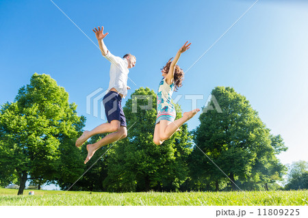 Couple in love jumping on park lawn 11809225