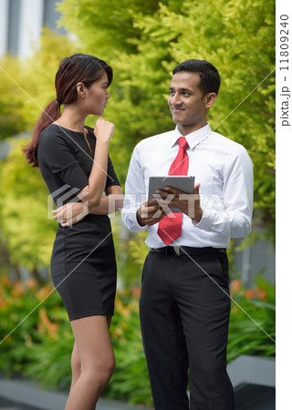 Mix race successful Indian Malay corporate execute meeting using iPad mobile device tablet outdoor 11809240