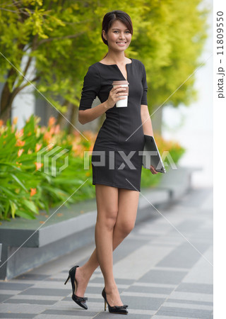Successful young Malay business woman with coffee cup and laptop along promenade during break time 11809550