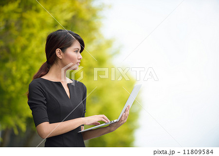 Successful young Malay business woman using laptop along promenade 11809584