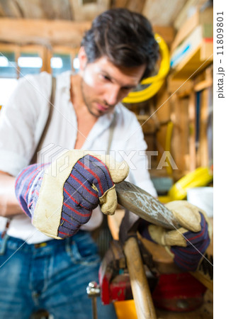 Young man sharpening tools in mountains hut 11809801