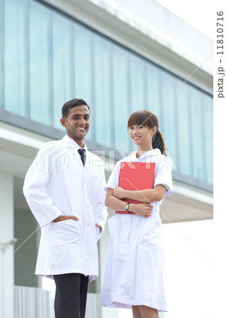 Successful young mixed race medical doctor and nurse standing in front of hospital 11810716