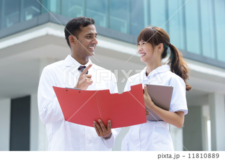 Successful young mixed race medical doctor and nurse in discussion in front of hospital Successful young mixed race medical doctor and nurse in discussion in front of hospital 11810889
