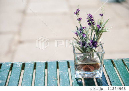 テーブルに置かれた四角いガラスの花瓶 紫の小さい花つきの写真素材