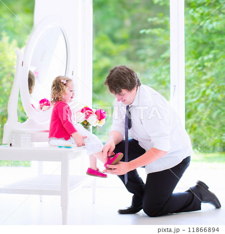 Father helping his daughter to put on a shoe Father helping his daughter to put on a shoe 11866894