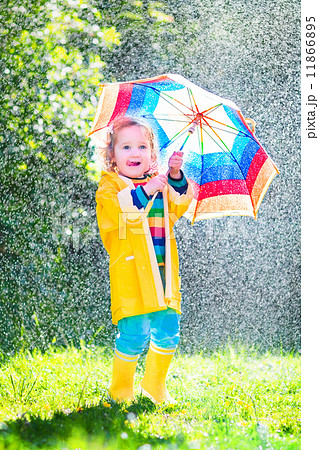 Funny toddler with umbrella playing in the rain 11866895