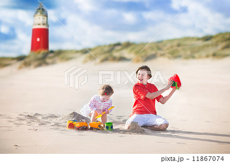 Brother and sister playing on the beach next to a lighthouse Brother and sister playing on the beach next to a lighthouse 11867074