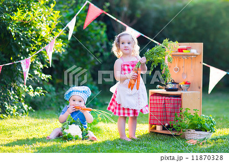 Little kids playing with toy kitchen in the garden Little kids playing with toy kitchen in the garden 11870328