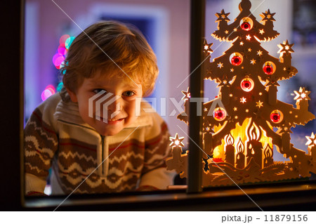 Smiling boy standing by window at Christmas time and holding can Smiling boy standing by window at Christmas time and holding can 11879156