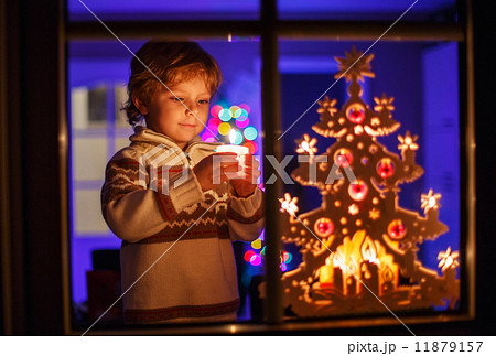 Smiling boy standing by window at Christmas time and holding can Smiling boy standing by window at Christmas time and holding can 11879157