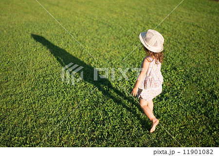 芝生で遊ぶ少女と影の写真素材