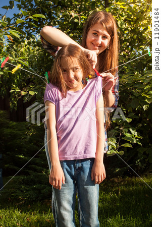 woman hanging girl on clothesline at garden 11901484