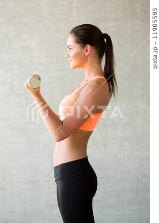 smiling woman with dumbbells in gym 11905595