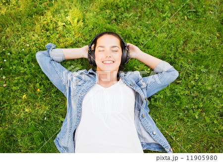 smiling young girl in headphones lying on grass smiling young girl in headphones lying on grass 11905980