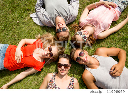 group of smiling friends lying on grass outdoors group of smiling friends lying on grass outdoors 11906069