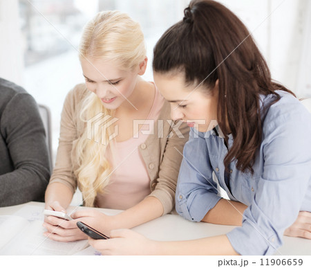 two teens with smartphones at school two teens with smartphones at school 11906659