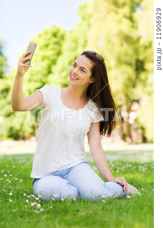 smiling young girl with smartphone sitting in park smiling young girl with smartphone sitting in park 11906929