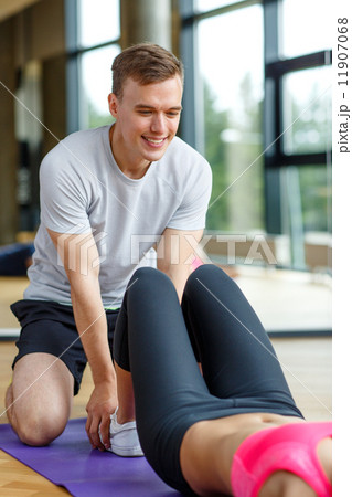 smiling woman with male trainer exercising in gym 11907068