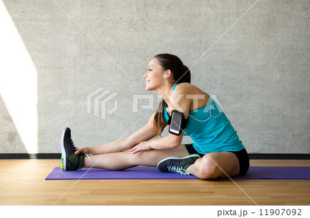 smiling woman stretching leg on mat in gym 11907092