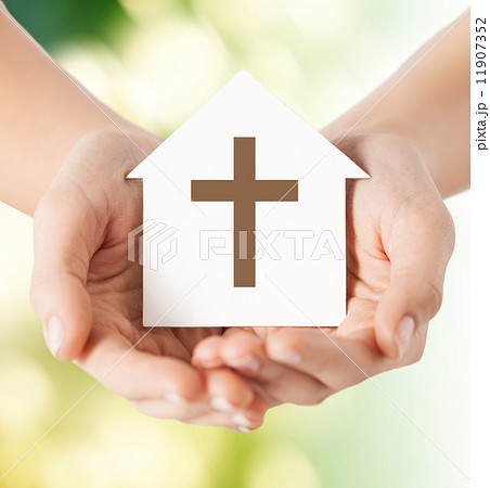close up of hands and paper house with cross 11907352