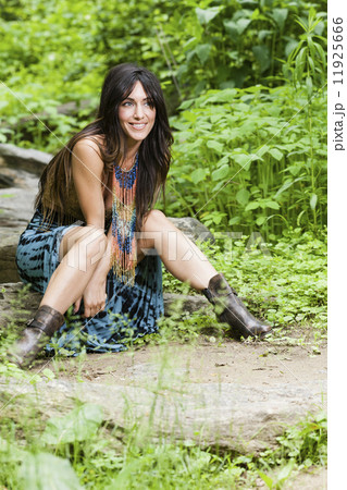 A woman with long brown hair outdoors in woodland. A woman with long brown hair outdoors in woodland. 11925666