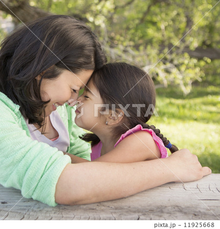 A mother in the park with her daughter, laughing and kissing each other. 11925668