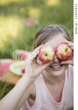 A girl holding two apples in front of her eyes A girl holding two apples in front of her eyes 11925813
